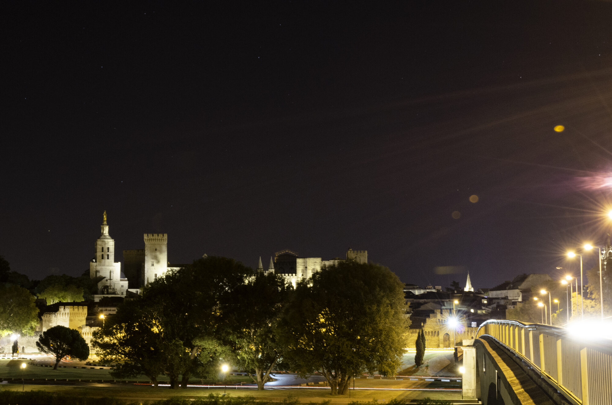 Beleuchteter Papstpalast in Avignon bei Nacht über der Rhône