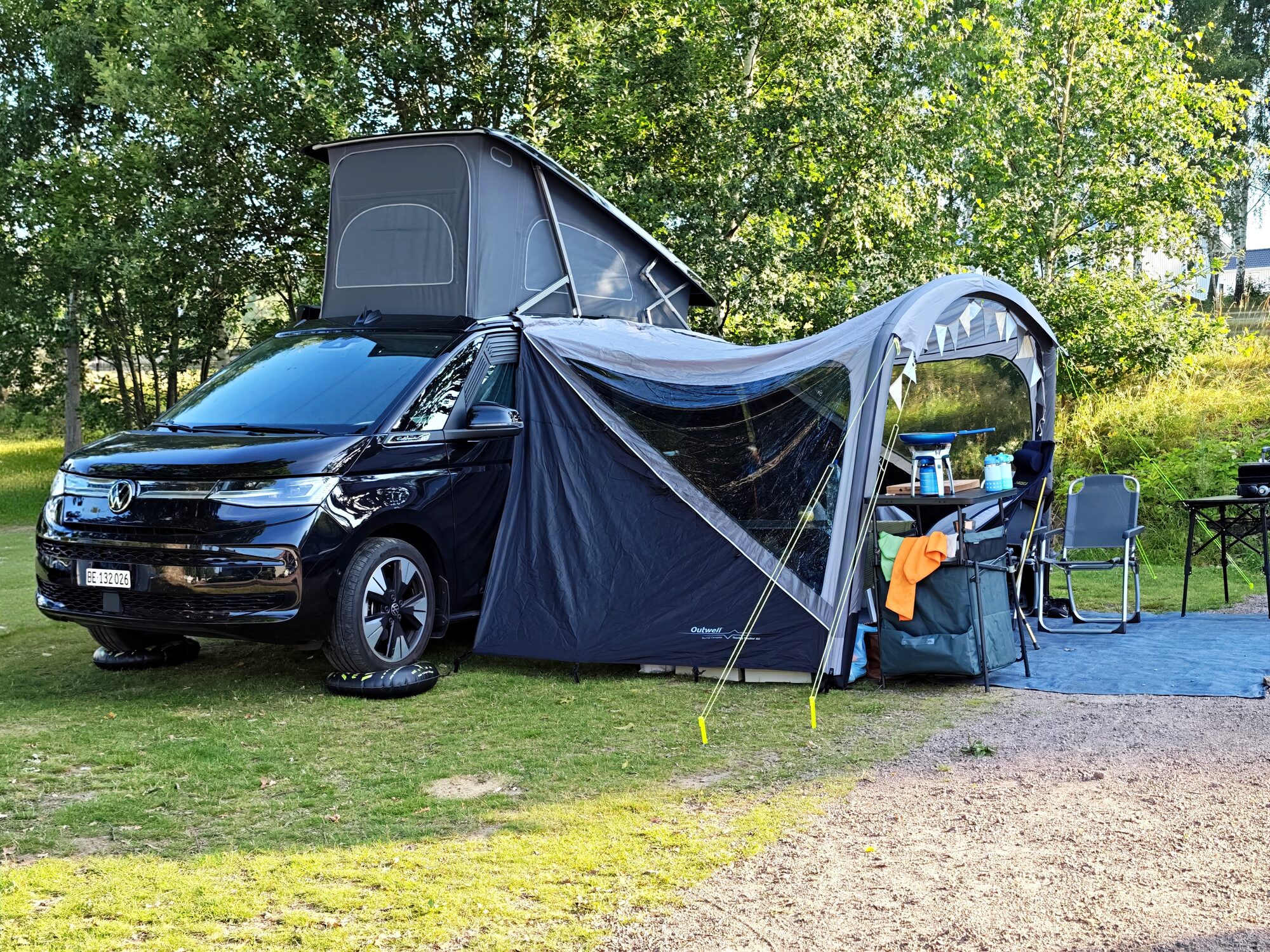 VW California mit aufgestelltem Dach und Vorzelt auf einem Campingplatz